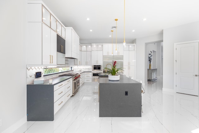 kitchen featuring decorative backsplash, premium appliances, pendant lighting, white cabinets, and a kitchen island