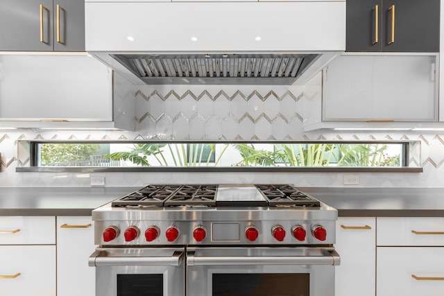 kitchen featuring backsplash, white cabinetry, double oven range, and range hood