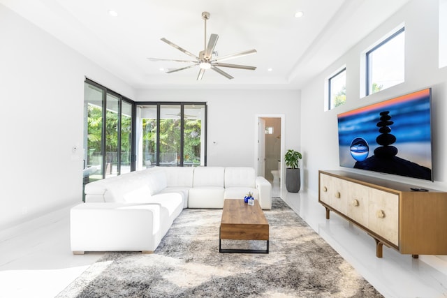 living room with ceiling fan and a tray ceiling