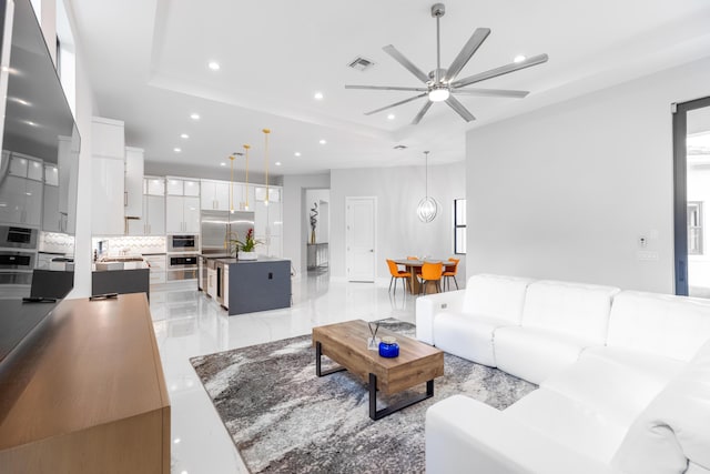 living room featuring a raised ceiling and ceiling fan