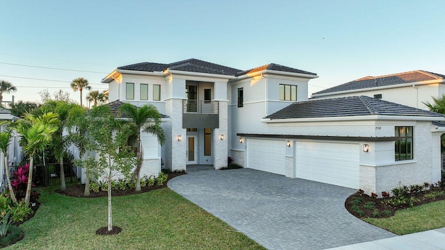 view of front of house with a balcony, a garage, and a front lawn