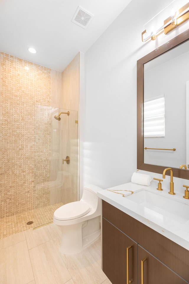 bathroom with a tile shower, vanity, and toilet