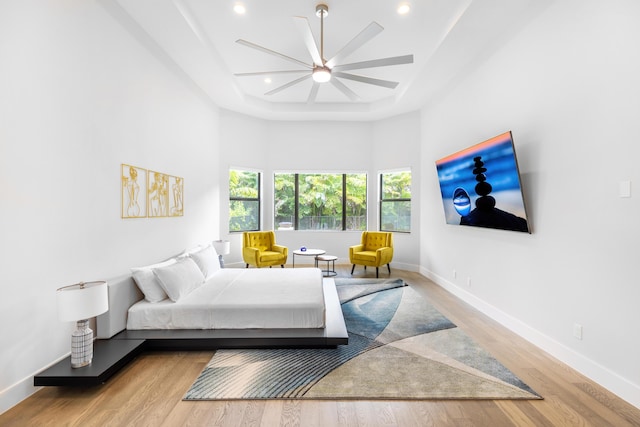 bedroom featuring a high ceiling, light wood-type flooring, and ceiling fan