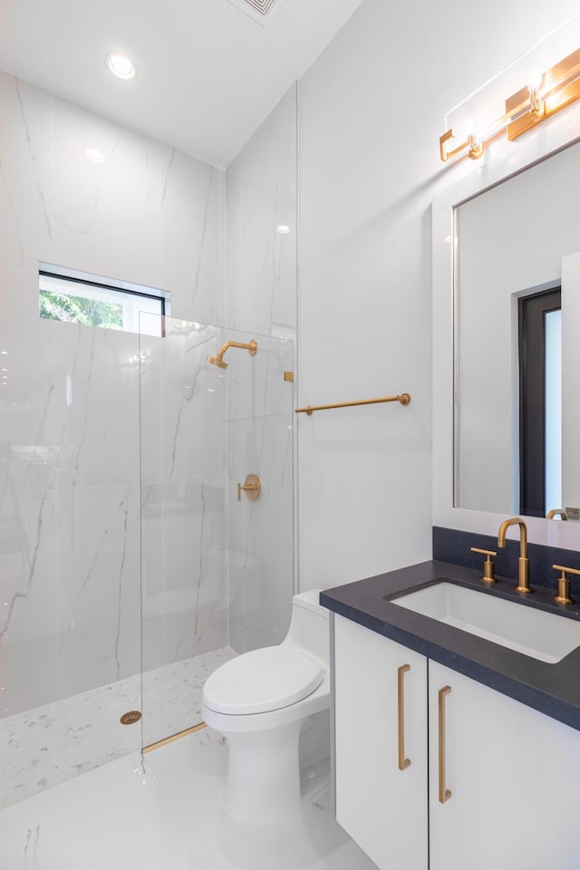 bathroom featuring vanity, toilet, and a tile shower