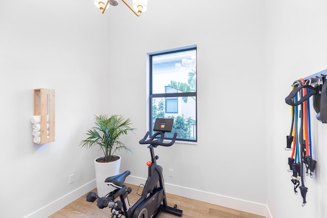 exercise area featuring hardwood / wood-style flooring and an inviting chandelier