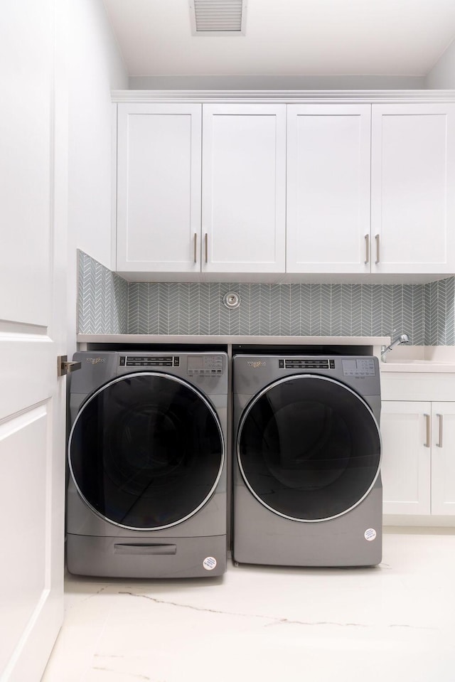 washroom with cabinets, separate washer and dryer, and sink