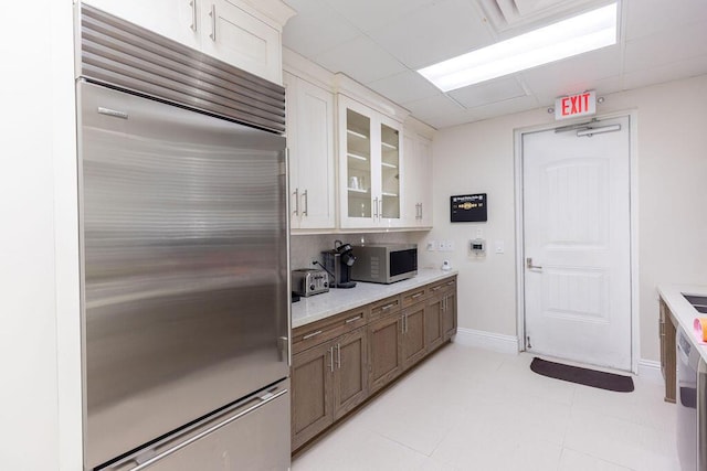 kitchen with white cabinets, a drop ceiling, and built in refrigerator