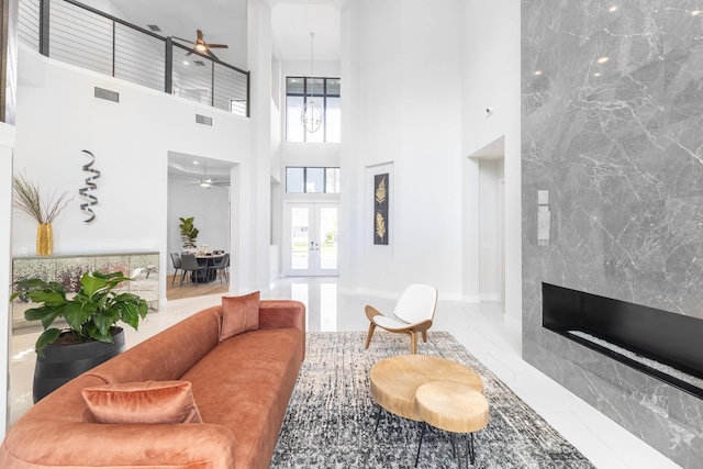 living room featuring a towering ceiling, a fireplace, and french doors