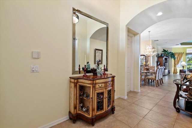 hallway with light tile floors and a notable chandelier