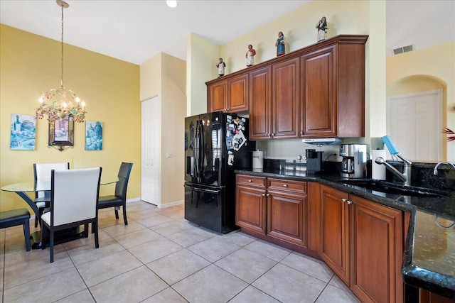 kitchen featuring black refrigerator with ice dispenser, light tile flooring, a notable chandelier, sink, and dark stone countertops