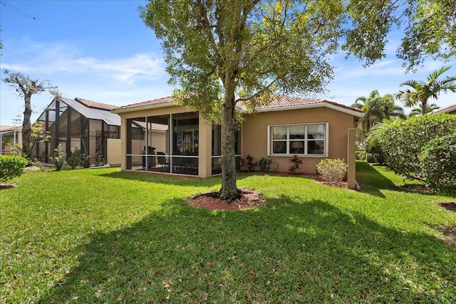 back of property featuring glass enclosure and a yard