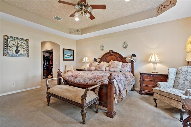 8839 Via Avellino, Lake Worth, FL 33467 - bedroom featuring light colored carpet, arched walkways, baseboards, a walk in closet, and a textured ceiling
