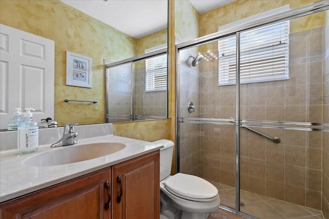 bathroom with oversized vanity, toilet, a shower with door, and a wealth of natural light