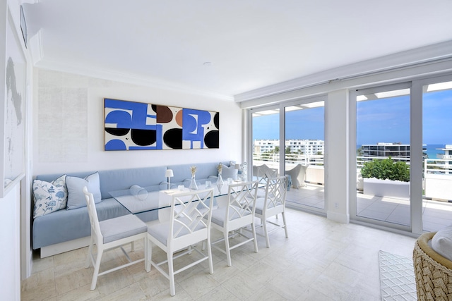 dining area with a water view, crown molding, and light tile flooring