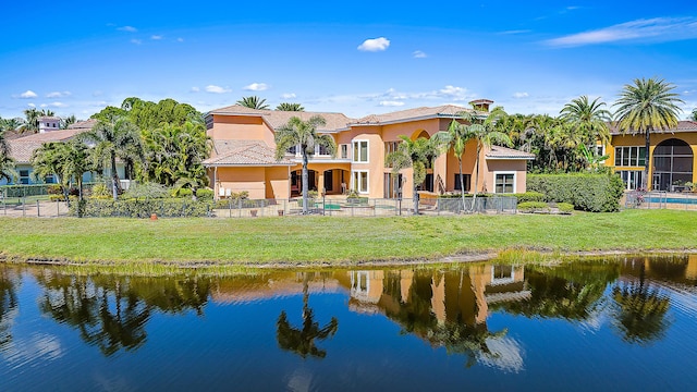 back of house with a water view and a lawn