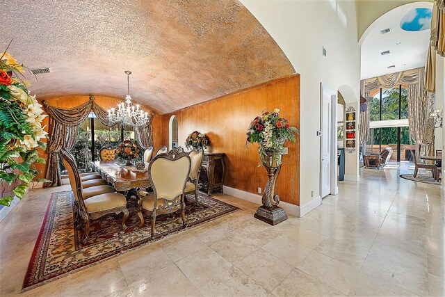 kitchen with a chandelier, an island with sink, light stone counters, and sink