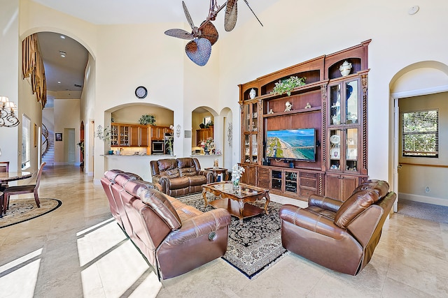 living room featuring ceiling fan and a high ceiling