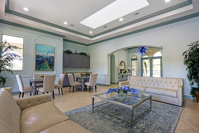 living room featuring ornamental molding, light tile patterned floors, a raised ceiling, and a skylight