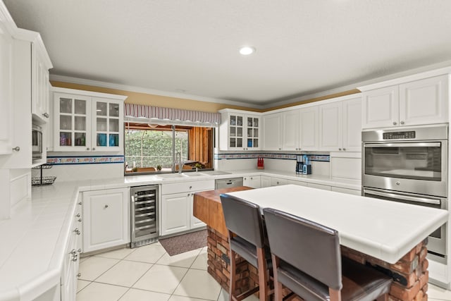 kitchen featuring sink, decorative backsplash, light tile patterned floors, beverage cooler, and white cabinets