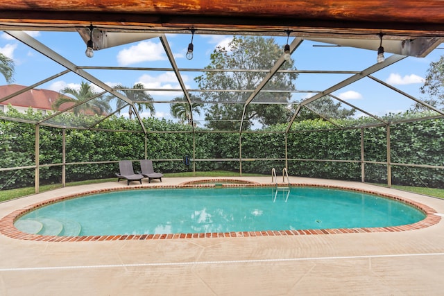 view of pool with an in ground hot tub, glass enclosure, and a patio