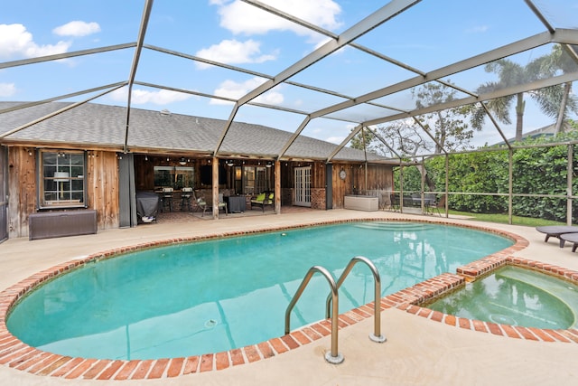 view of pool featuring an in ground hot tub, glass enclosure, and a patio area