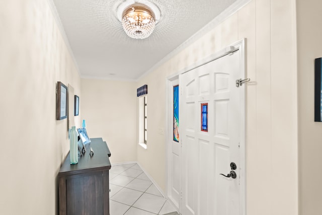 tiled foyer entrance with a notable chandelier, a textured ceiling, and ornamental molding