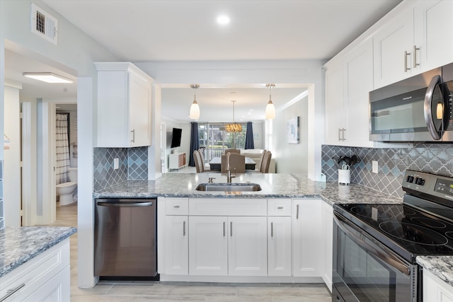 kitchen featuring stainless steel appliances, light stone countertops, tasteful backsplash, light hardwood / wood-style flooring, and hanging light fixtures