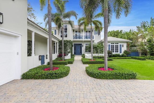 view of front of home with a front yard, a balcony, and a garage