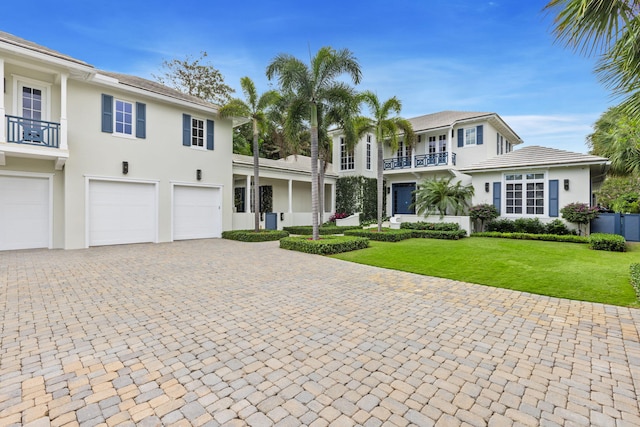 view of front facade featuring a balcony, a garage, and a front lawn