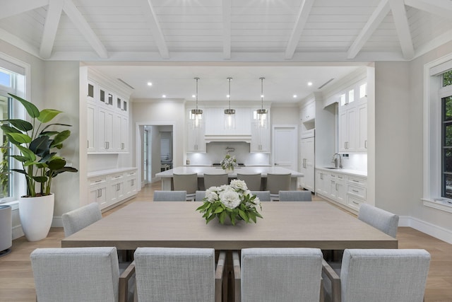 dining area with light wood-type flooring, lofted ceiling with beams, sink, and wooden ceiling