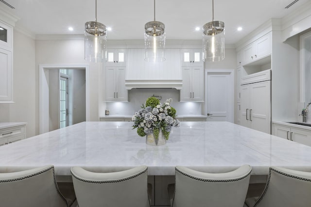 kitchen featuring a kitchen breakfast bar, hanging light fixtures, and white cabinetry