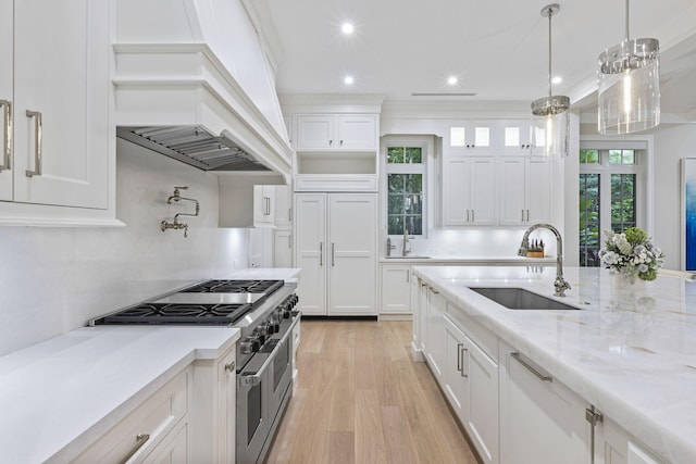 kitchen with premium appliances, pendant lighting, sink, and white cabinets