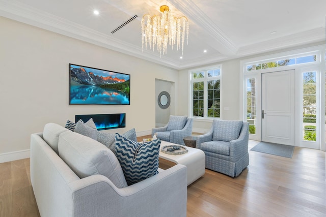 living room featuring light wood-type flooring, ornamental molding, and a chandelier