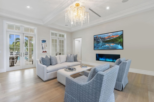 living room featuring crown molding, light hardwood / wood-style floors, a chandelier, and french doors