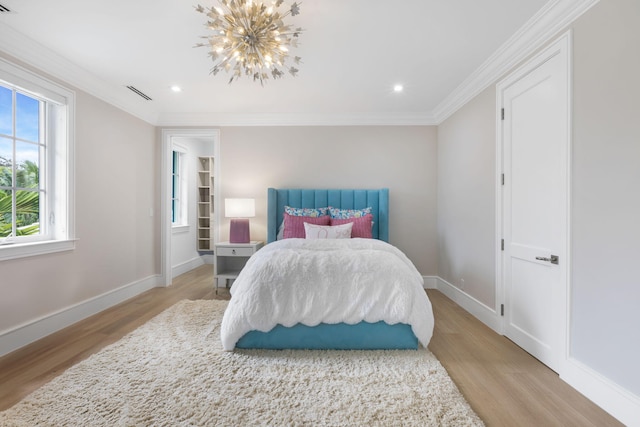 bedroom featuring ornamental molding, light hardwood / wood-style floors, and an inviting chandelier