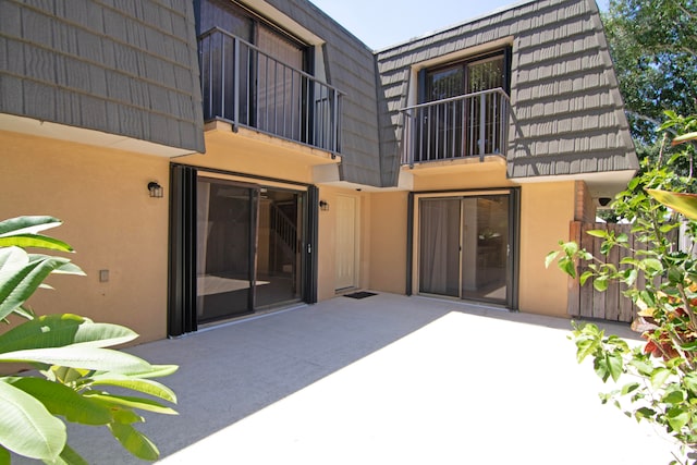 back of property featuring a balcony and a patio