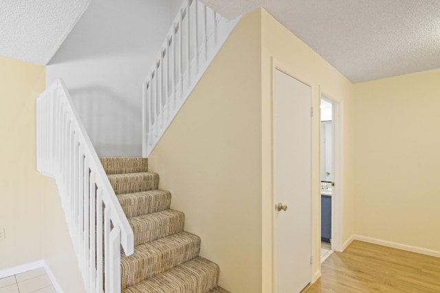 stairway featuring light hardwood / wood-style floors and a textured ceiling