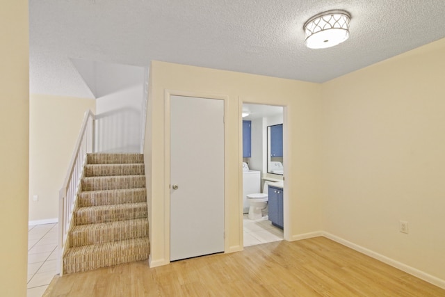 interior space with washer / dryer, light wood-type flooring, and a textured ceiling