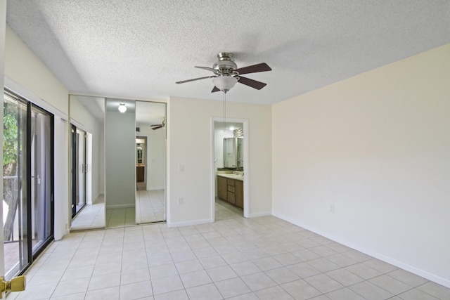 spare room with a textured ceiling, light tile patterned floors, and ceiling fan