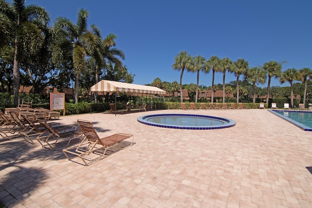 view of swimming pool featuring a hot tub and a patio area