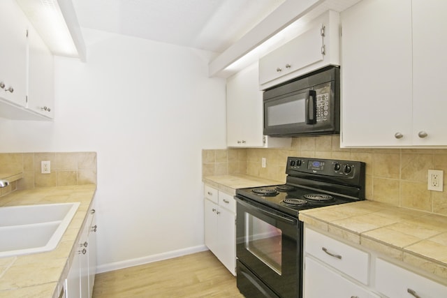 kitchen with light hardwood / wood-style floors, sink, black appliances, and white cabinets