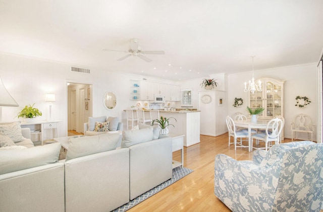 living room featuring ornamental molding, light hardwood / wood-style floors, and ceiling fan with notable chandelier