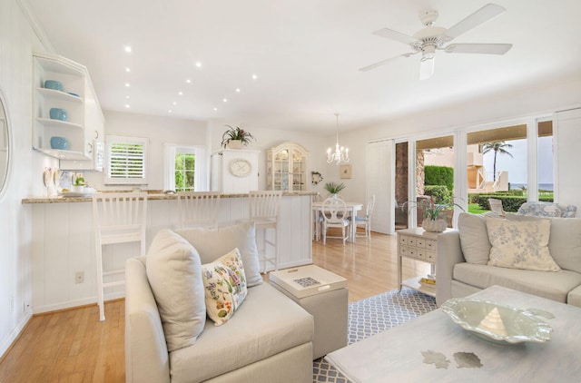 living room featuring light hardwood / wood-style floors and ceiling fan with notable chandelier