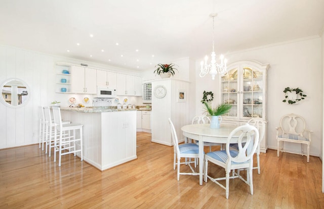 dining room featuring crown molding, a chandelier, and light wood-type flooring