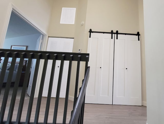 staircase with a barn door, wood-type flooring, and a high ceiling