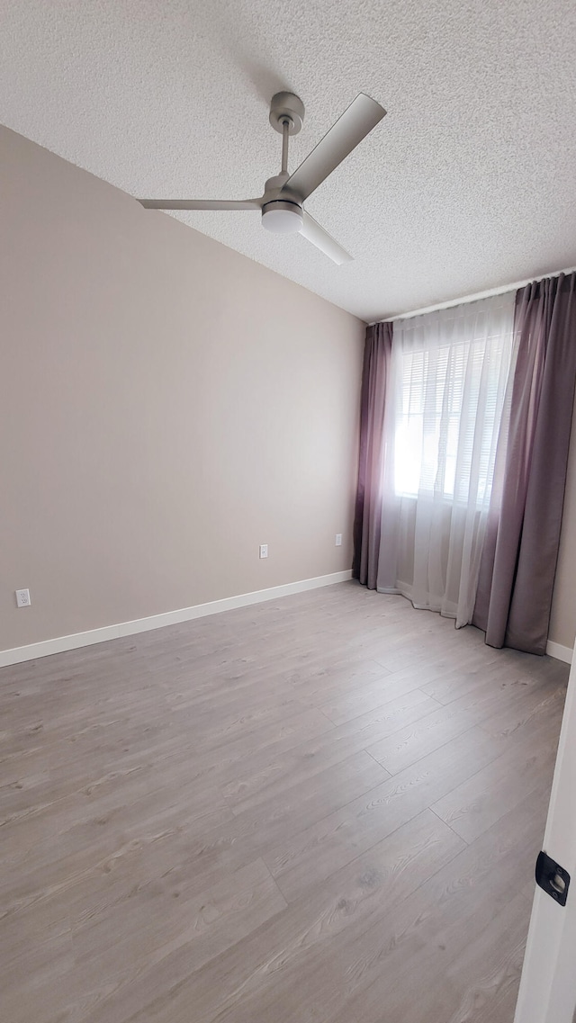 empty room with ceiling fan, light hardwood / wood-style floors, and a textured ceiling