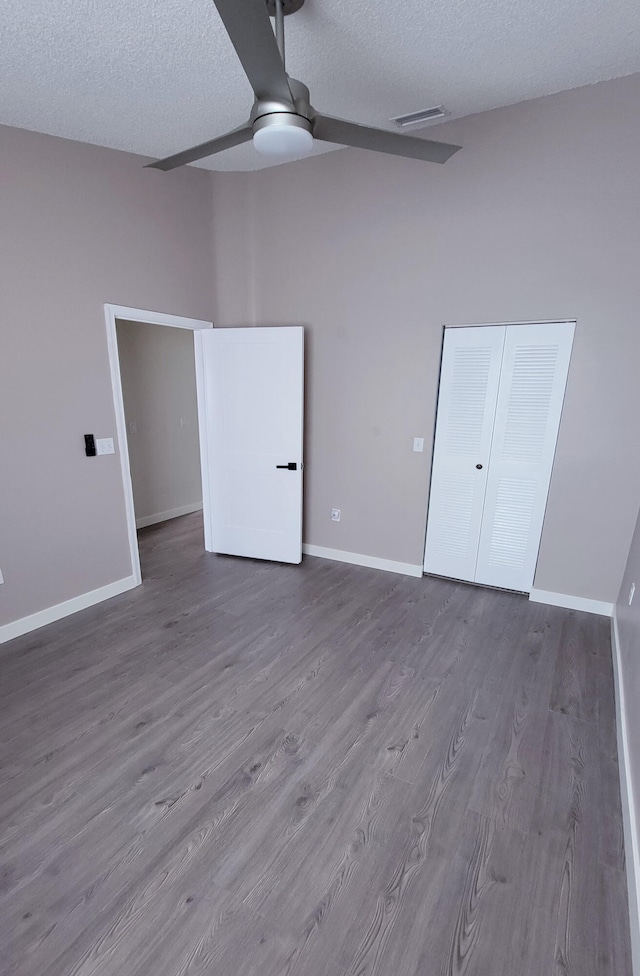 unfurnished bedroom with ceiling fan, a closet, hardwood / wood-style floors, and a textured ceiling