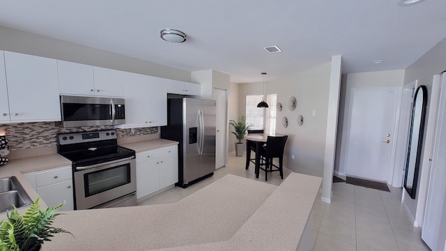 kitchen featuring backsplash, decorative light fixtures, appliances with stainless steel finishes, and white cabinetry