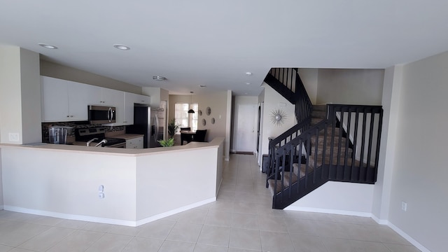 kitchen featuring stainless steel appliances, white cabinets, kitchen peninsula, light tile patterned floors, and backsplash