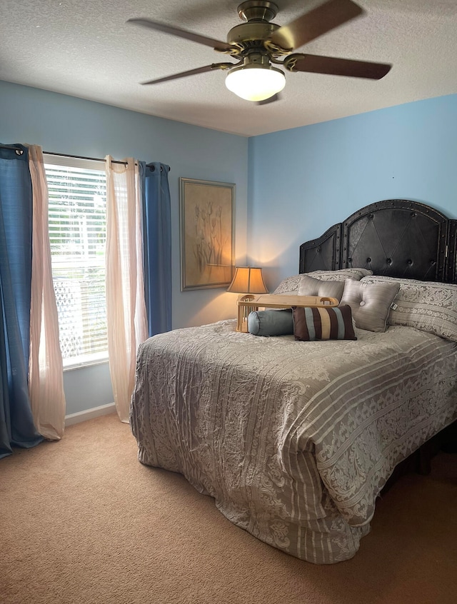 bedroom with ceiling fan, carpet floors, and a textured ceiling